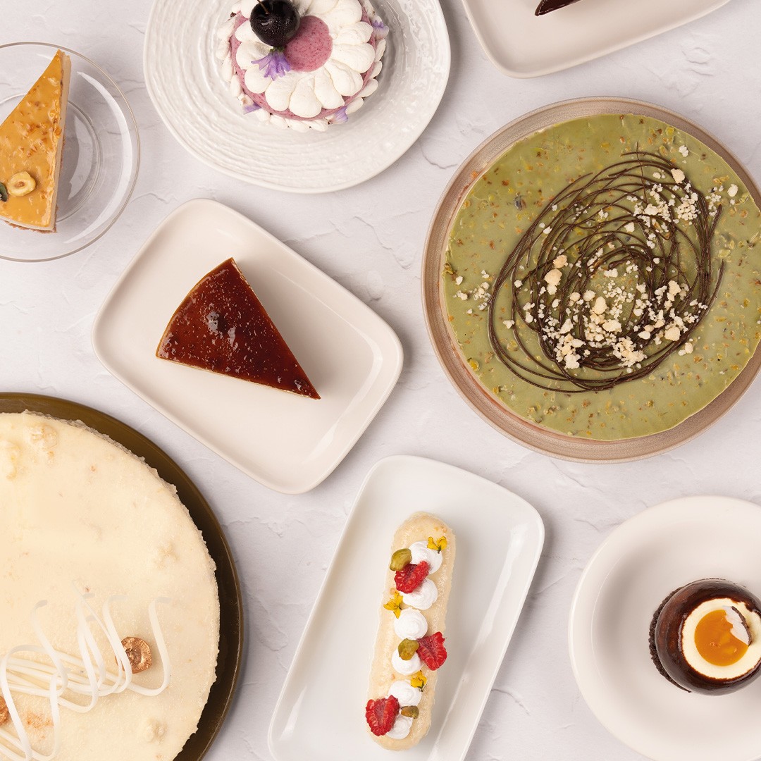 Pandangan atas pelbagai pencuci mulut termasuk kek keju, flan, tart pistachio, eclair dan mousse coklat cawan